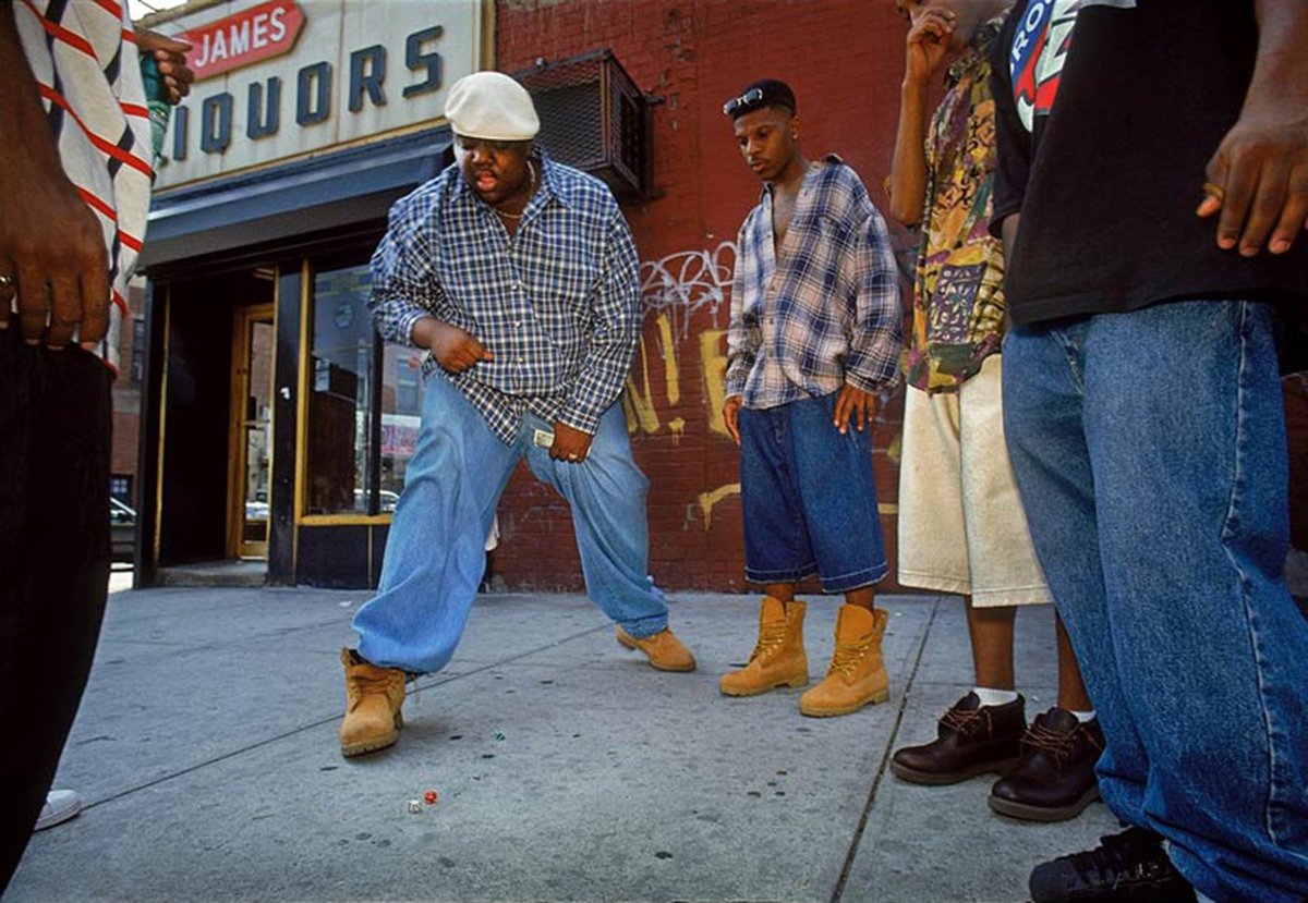 The 𝐍𝐨𝐭𝐨𝐫𝐢𝐨𝐮𝐬 𝐁.𝐈.𝐆., photographed by 𝐌𝐚𝐧𝐮𝐞𝐥 𝐀𝐜𝐞𝐯𝐞𝐝𝐨, plays a dice game on a Brooklyn sidewalk, 1994.