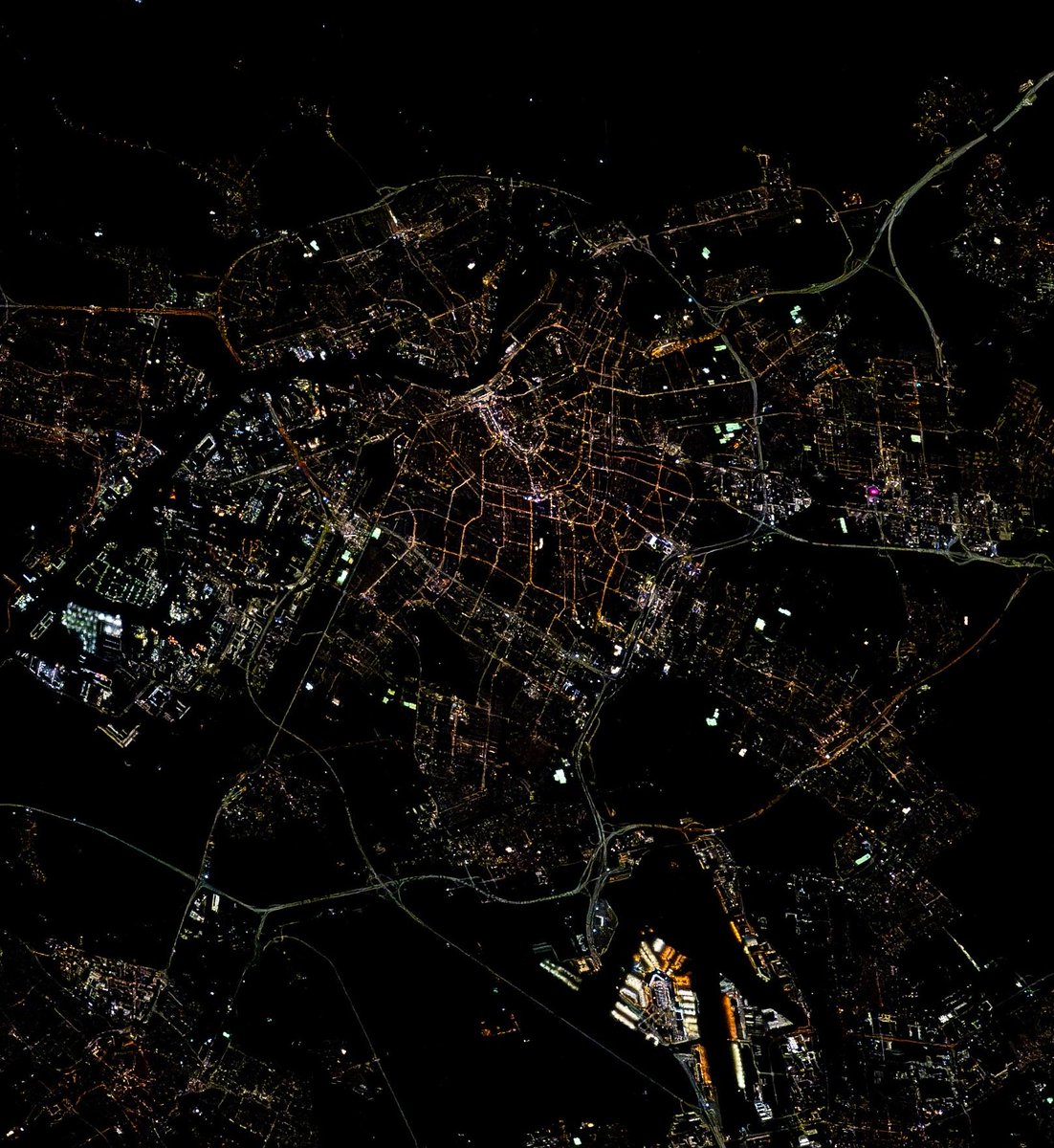 astro_Pettit's tweet image. Amsterdam, Netherlands seen at night from the ISS. The city's famous canals and waterways cut distinct lines of darkness around modern lights.