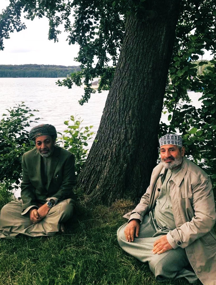 AlsiyabiHamood's tweet photo. مات أبو خالد ! ولكنه لن يرحل 
——————————
 حمود بن سالم السيابي 
——————————
أعرف أن هذا المسجَّى أمام المصلين هو أنت. 
وأنك على غير عادتك في الدخول لبيوت الله ، لم تتقدم نحو المحراب لتقف إماما.  
ولا توسَّطْتَ الواقفين لتكون سترة. 
وأعرف إن نصف الصلاة عليك بكاء. 
ونصفها حيرة ودهشة وأسئلة وعودة موجعة للبكاء. 
 وأعرف أنك مت ، ولكنَّ منْ له في كل ظل وشيجة مع الشجر لن يرحل ، بل سيتكاثر الشجر بالسُّقْيا وسيتَّسع بالضرورة الظل الأخضر. 
ولقد سبقَ وفُجِعَتْ عمان بموت سيدنا الرضي والدك وكان الجميع في المح��ر النخلي فهو علَّامة عصره ، و"موت العالمِ ثلمة في الإسلام لا تُسَدْ". 
وفُجِعْنا بموتك يا أبا خالد وضاقتْ نخل من جديد بما رَحُبَتْ وامتلأتْ السِّكَك ببشر لا نعرفهم ولكنهم عرفوا ��آثرك. 
وكانت المقبرة محشرا نخليا آخر ، لا لأنك نجل العلامة ، بل لأن للأحباب تقديراتهم الوازنة فتساوتْ نظرتهم في أعلميَّة ومكانة والدك ، وفي استحقاقات حزْمة المآثر عندك. 
لذلك جاءوك من كل حدب وصوب في استفتاء نبيل عليك. 
وقد جاهدتُ في تثليج مشاعري بين صلاتي الجمعة والعصر لأتمكن من رؤيتِكَ في أعين الناس ، ولأقرأك فيهم وهم يبكونك كما لم يبكوا أقرب الناس إليهم فخذلتني قدراتي في تثليج المشاعر فبكيتك. 
بكيتُ طفولة جمعتنا رغم أنني الأسَنّ ولكنك دوما الأكبر. 
وبكيتكَ تحسَّرا لتضييع العمر فلم أقدر على مجاراة رجل حفظ القرآن وتعلمه وعلَّمَه. 
وبكيتُ غُررَ الوضوء وحمام�� المسجد ، والوجه الساجد. 
وبكيتُ سفرا جمعنا في "بمبي" صحبة والديْنا وكنتَ نعم الابن البار بأبيك ونعم الصاحب في الس��ر. 
ولربما لو تحدثتْ بوابة الهند وشوارع "كلابا" لقالتْ فيك ما لم يقُله طاغور في ديوان "قربان الأغاني". 
وتوافقنا دون ترتيب مسبق سوى الشوق لمكة المكرمة الذي حجز تذاكره وفنادقه فالتقينا هناك لنترع من ماء زمزم ونتضلَّع ، لعل شربة منها تتبعها شربة من الحوض الأصفى. 
وجمعنا ظلُّكَ الأخضر في سكنكَ ب"بون" فمشينا ذات جمعة زهراء واقتربنا من منزل لآخر سفير عماني في "بون" قبل أن تعيد الوحدة الألمانية الاعتبار لبرلين ، وكيف أن صاحب البيت الألماني ظل محتفظا بلافتة السفير العماني على منزله ، فكنت تُكْبِر هذه الالتفاتة النبيلة في صاحب البيت واعتبرت مسلكه يمثلك. 
وضمَّتنا ضفاف بحيرة "أليستر" في هامبورج وأنت تنضم فيَّ قصيدة لا أستحقها فلم أنشرها واكتفينا بالانصات لنافورة هامبورج ، وما أكثر قصائدك في الآخرين وما أجمل روحك الشاعرة. 
والتقينا على ضفاف بحيرة "رينبك" وكانت قصيدة أخرى تنتظر يراعك ليرصعها بأجمل ما قاله فيها الألمان. 
وافترشنا ظل شجرة في "مولن" بمنطقة "شيليزفيج هولشتاين" الألمانية ومعنا بعض الرطب الذي حملتَه زاداً من عمان.
ولعل النَّوى الذي لفظناه هناك قد استسقى البحيرات فكبر النخل بجوار شجر الزان والسرو والصنوبر فللارض من أيادي الخيِّرين نصيبها. 
وجمعتْنا عاصمة "سيام" ونحن في مستشفى "بمبرونجراد" نتحلق حول فراش الرضية والدتك في ليلتها الأخيرة قبل اللحاق برفيق عمرها سيدها السعيد فكنتَ تنزف وجعاً لأن أمنياتك أن تعود للوطن ووالدتك مع�� فقد اشترت "الصوغات" فلم تشأ الأقدار. 
وكما كنتَ جميلا في الحياة ، فكنت الأجمل وأنت تضع الخاتمة لنصِّك المرصَّع بالأوسمة. 
ساعتها خرجْتَ كعادتك في كل جمعة بدشداشة بيضاء ذات "فريخة" مغموسة في خياراتك من العطر ، ولوَّحتَ بكفك لدخان "المجمر" الذي يفرقع بذوبان حطب العود ، وتأبَّطْتَ بشتك البني بلون النهار وخطبة الجمعة مطوية في يديك وودعت. 
وفي المسافة القصيرة بين عتبة البيت وباب جامع السيد ماجد بن تيمور كنت تهلل وتكبر وتصلي على سيد البشر. 
دخلتَ الجامع واعتليتَ المنبر وسلمتَ وخطبتَ في المصلين عن الصلاة عماد الدين ، ثم جلست بين الخطبتين وأتممتَ خطبتك بدعوة المؤمنين بالصلاة على خير الخلق أجمعين ، فكانت آخر جملة لآخر خطبة لآخر التفاتة للوجوه أمامك وهم يرطِّبون الشفاه بالصلاة. 
لقد انتهى التكليف ، وشيخنا محمد بن سعيد بن خلف الخروصي على موعد بإذن الله بمكان غير المكان ، وبجوار غير الجوار. 
لذلك سأظل أكرر يا أبا خالد أنَّكَ مت.
ولكنكَ لم ترحل. 
 ولن ترحل. 
———————-
مسقط في الجمعة الزهراء ١٥ محرم ١٤٤٧هـ الموافق ١١ يوليو ٢٠٢٥م.