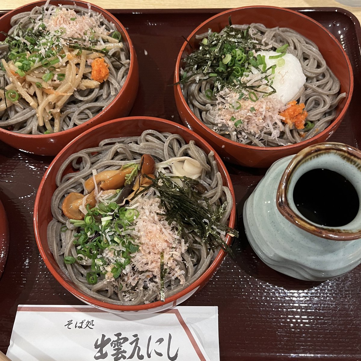 cookingwithdog's tweet photo. We had three hours of free time at Izumo Taisha. ⛩️👩‍🍳😍 First, I visited Inasa Beach, where it is said that all the deities from across Japan gather on the 10th day of the 10th lunar month. After that, I headed to Izumo Taisha and paid my respects at the main sanctuary. There are many shrines and points of interest within the grounds, so I enjoyed a leisurely stroll while taking it all in. Izumo Taisha is a sacred place enshrining deities from Japanese mythology, and the entire area was filled with a solemn and divine atmosphere.

For lunch, I went with a fellow tour participant to Soba-dokoro Izumo Enishi, a soba restaurant located right near Izumo Taisha. I ordered the popular Sanshoku Warigo Soba, which features three servings of soba noodles topped with mountain vegetables, kinpira gobo (burdock root), and grated yam.

You add condiments and pour dashi broth over the noodles before eating. The soba was darker and thicker than that found in the Kanto region, and I enjoyed its firm, chewy texture. It was my first time trying Izumo soba, and it was delicious!

出雲大社では3時間の自由行動がありました。
まず、全国の神様が旧暦10月10日に集まるとされる、稲佐の浜を訪れました。
その後、出雲大社に向かい、御本殿を参拝。
境内には様々な社殿や見どころがあるので、ゆっくりと散策しながら楽しみました。
出雲大社は、日本神話に登場する神々が祀られている場所で、厳かで神聖な雰囲気に満ち溢れていました。

昼食は、ツアーで仲良くなった方と一緒に、出雲大社のすぐ近くにある「そば処　出雲えにし」へ。人気メニューの「三色割子そば」を注文しました。

山菜、きんぴらごぼう、とろろがのったそばが3枚。これに薬味をのせ、だし汁をかけていただきます。関東の蕎麦より黒くて太く、しっかり噛んでいただきました。初めての出雲そば、おいしかったです！
