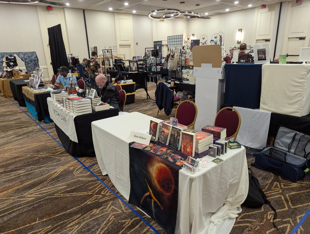 GCDaveDobson's tweet image. Hawking stuff at ConGregate. The guy at the next table is convention guest and Star Wars novels author Timothy Zahn. He's getting a lot more business than I am. Past him is noted author Milton Davis.