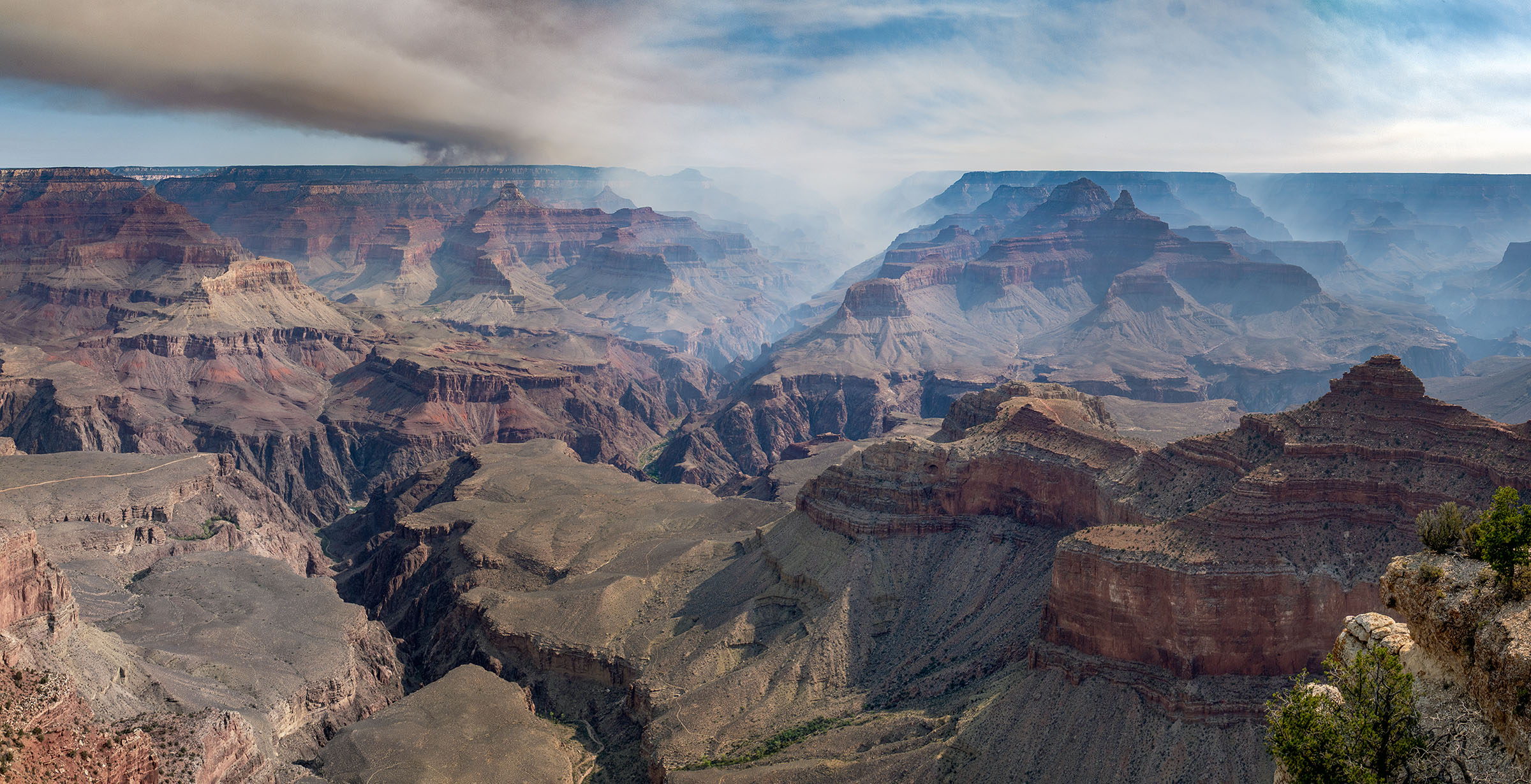 Smoke billows through a canyon landscape