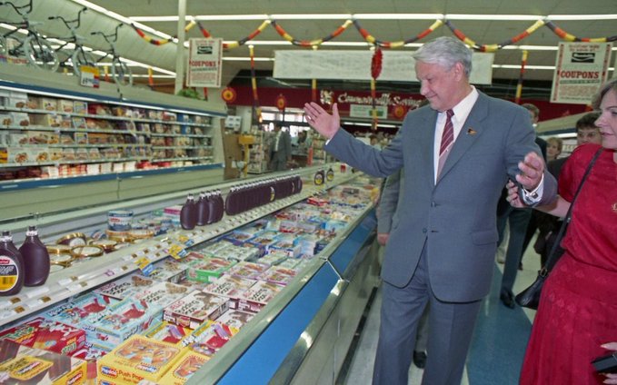 A vintage photo of a man in a suit gesturing in a well-stocked grocery store aisle, used as a meme for blockchain blockspace