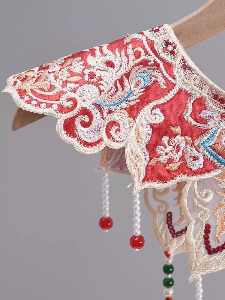 ManusxMachina's tweet image. 唐草と蝶の刺繍付け襟 
manus-machina.com/collections/ne… 
鮮やかな赤地に緻密な金糸や色糸の刺繍がほどこされ、花鳥や唐草模様のような伝統文様が贅沢に広がっています。動きに合わせて軽やかに揺れるパールチェーンは、まるで祝宴の光を受けて煌めくシャンデリアのよう。