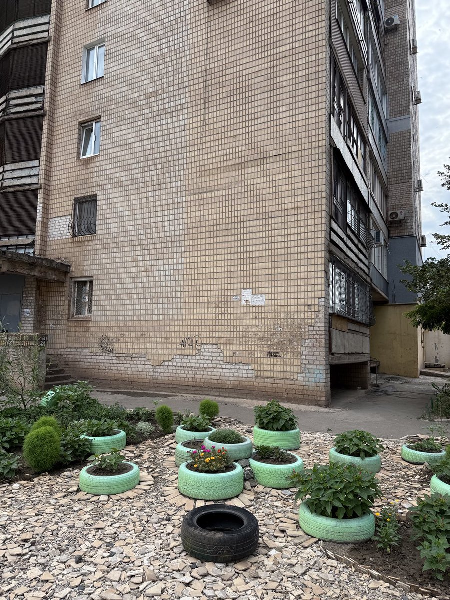 3Bergen's tweet image. Deze dame verfraait de tuin naast haar flat met gebruikte autobanden -die ze steevast mintgroen schildert- en tegels die nu en dan van het gebouw naar beneden kletteren. #KryvyiRih