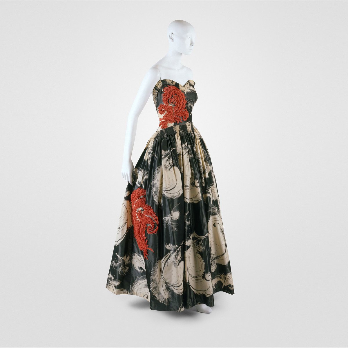 TheVFG's tweet image. Jeanne Lanvin’s "Fusée"
This 1938 evening gown juxtaposes warp-printed ostrich plumes in cream and black with vibrant coral ribbon appliqué. The name Fusée—suggestive of motion, brilliance, and perhaps a spark of flight.
Metropolitan Museum of Art