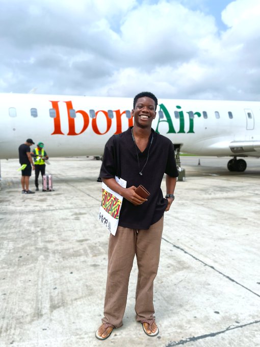 Ibom Air 비행기와 Lagos 표지판을 들고 있는 여행자
