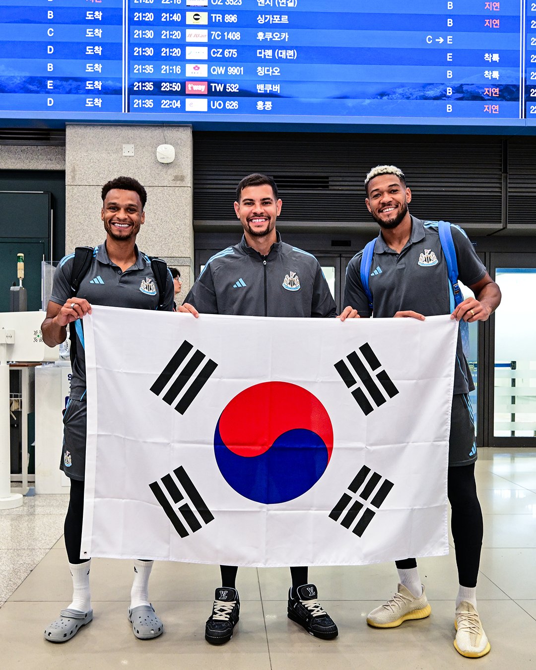 Jacob Murphy, Bruno Guimarães and Joelinton posing with the flag of South Korea
