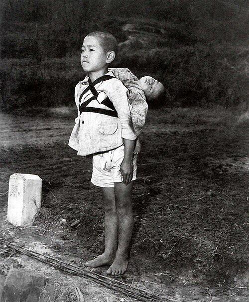 HistorylandHQ's tweet image. A Japanese boy standing at attention, carrying his dead younger brother on his back, waiting for cremation after the Nagasaki bombing (1945).