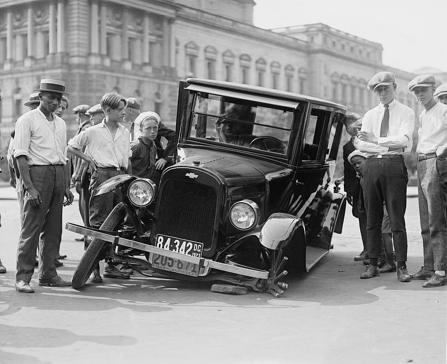 curious_ledger's tweet image. A crowd gathers in 1923 to inspect a broken-down Chevrolet in the heart of the city. The left front wheel has completely snapped off—an all-too-common sight in the early days of motoring. Back then, every car problem became a public spectacle.