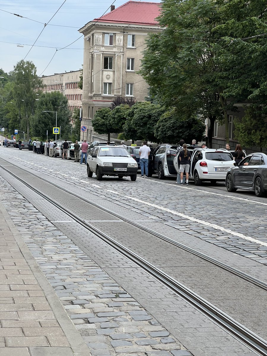 Mrchk0's tweet image. Photo prise aujourd’hui à Lviv en Ukraine : les automobilistes s’arrêtent et sortent de leurs voitures au passage du cortège funéraire d’un soldat tombé au front. Scène devenue malheureusement banale ici, mais toujours aussi poignante.