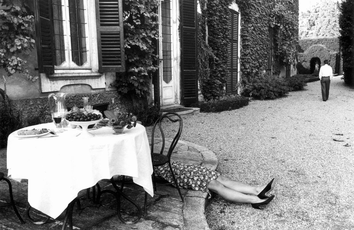 ospuac's tweet image. La mesa aún conserva el vino servido y el pan intacto. Solo el vestido floreado asoma bajo la silla, como si el almuerzo hubiese sido demasiado.
Él se aleja sin mirar atrás, mientras el silencio del jardín oculta el último suspiro.