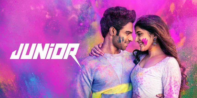 The image features Kireeti and Sreeleela, two actors covered in colorful Holi powder, standing close together with affectionate expressions, set against a vibrant pink and purple background with splashes of color. The text "JUNIOR" is prominently displayed in bold white letters on the left side, indicating the film\'s title. The post review highlights Kireeti\'s remarkable screen presence, Sreeleela\'s charm, and dynamic elements like the Viral Vayyari Song and action sequences, suggesting a focus on their performances and the film\'s dance and action highlights. No platform watermarks are visible.