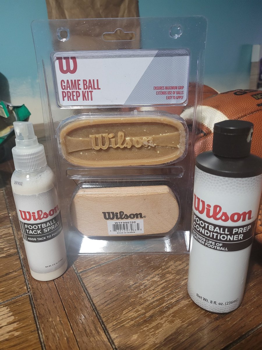 When your QB's don't like new footballs, you condition them instead of giving them to your Punter/Kicker to break in. Whatever it takes for our guys. 

Some like to mud treat footballs. If you're looking for an alternative, I suggest Wilson Game Ball Prep Kit.