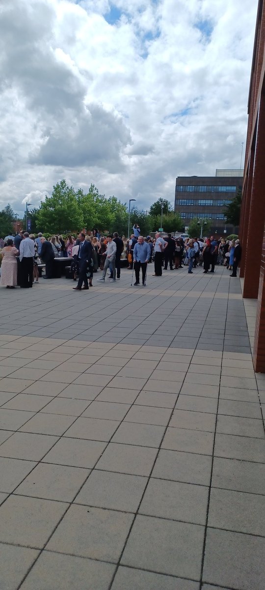 Family and friends of the latest graduation cohort watching the graduates form up for the cap throwing photo.