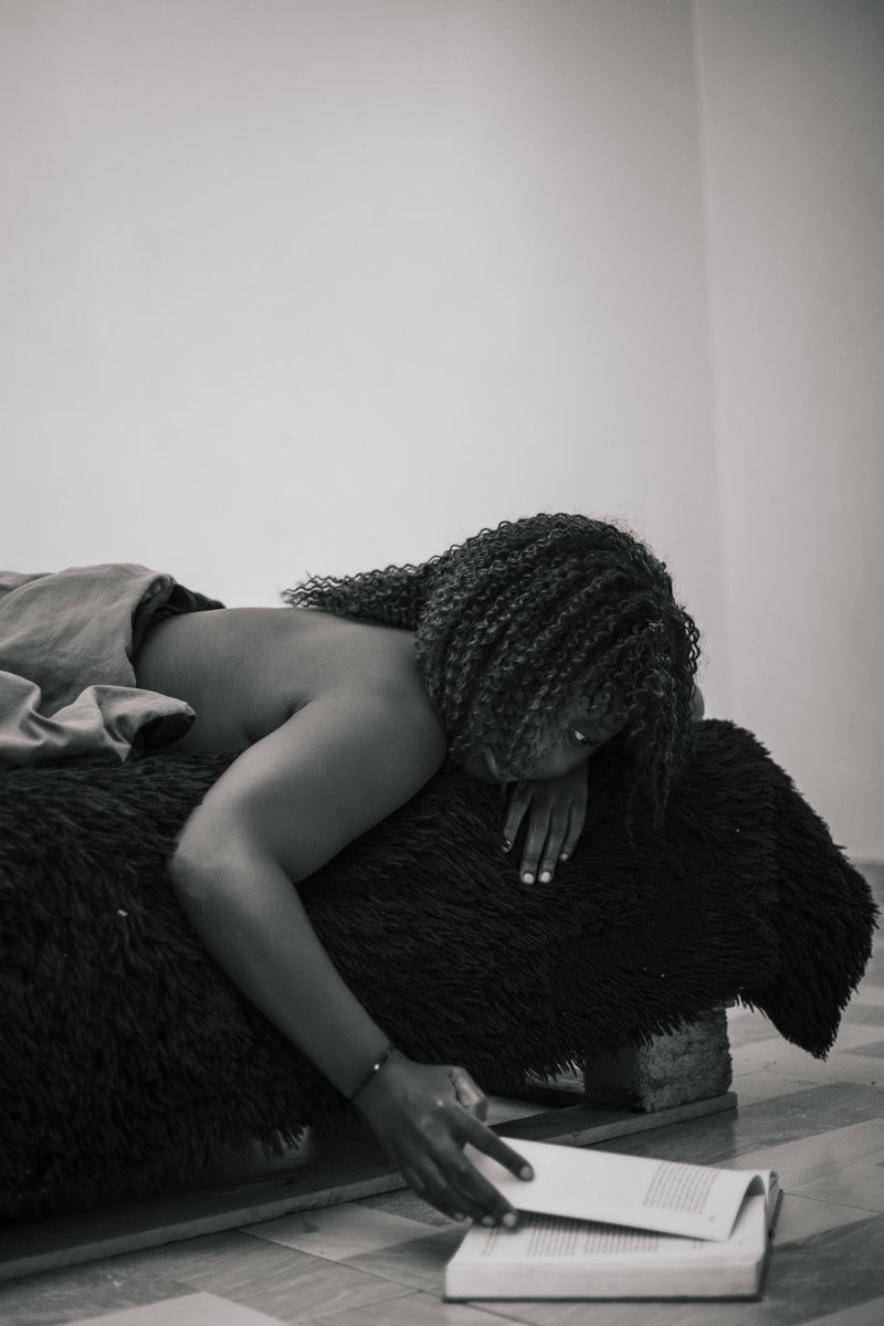 Flicks - Bodies and Pages
photographed by twinomugisha

A figure reclines beneath a plush blue blanket, the texture of fur and wool folding gently around a quiet body. Light filters in from an unseen window, tracing the curve of a bare shoulder. The reader’s breath seems to