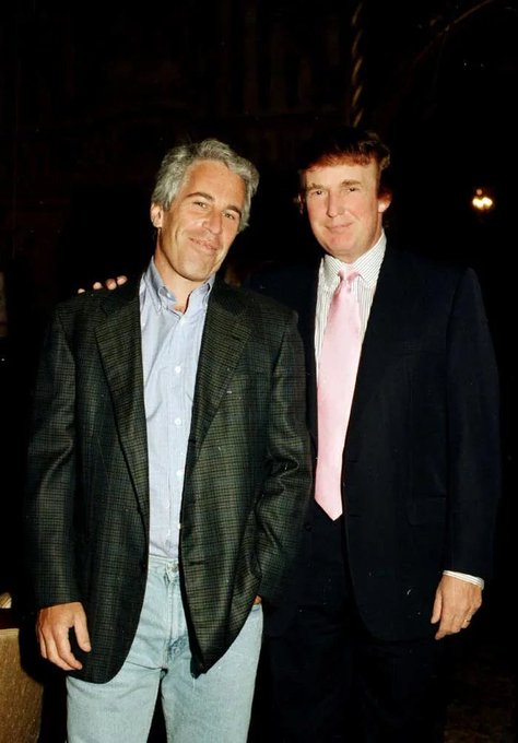 The image shows two men standing side by side, smiling, in a formal setting at night, possibly at an event. The man on the left has gray hair, wears a dark blazer, light blue shirt, and jeans, while the man on the right, identified as Donald Trump from the post context, wears a dark suit and pink tie. The post text from Fonsi Loaiza references a Wall Street Journal article about a controversial birthday card Trump sent to Jeffrey Epstein, implying a connection between the two, though Epstein is not in the image. No platform watermarks are visible beyond the Instagram link context.