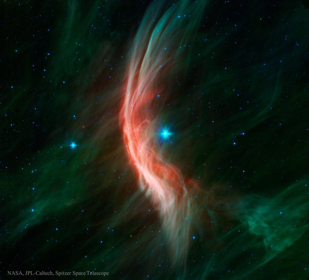 Este espectacular paisaje es producto de la estrella Zeta Ophiuchi, que produce un arco de choque a medida que avanza por el espacio. En esta imagen (en falso color, tomada en infrarrojo), la estrella está en el centro de la imagen. Es 20 veces más masiva que el Sol y se mueve