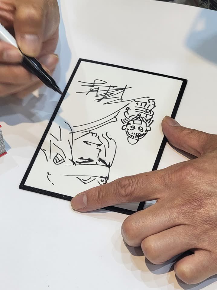 RoT_eng's tweet image. 🎉 || The Facebook account has shared pictures of Chan Mou and some of his illustrations at the signing event - and he’s even wearing one of the new Eight Geniuses shirts that debuted at the Book Fair!