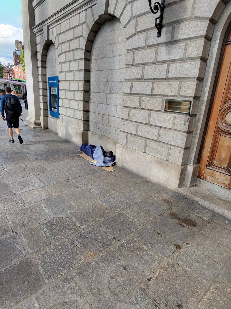 Editorialz's tweet image. For this homeless person outside the central bank, what a horribly cruel existence. Lying in an unprotected archway on solid granite with nothing but a sleeping bag to your name.