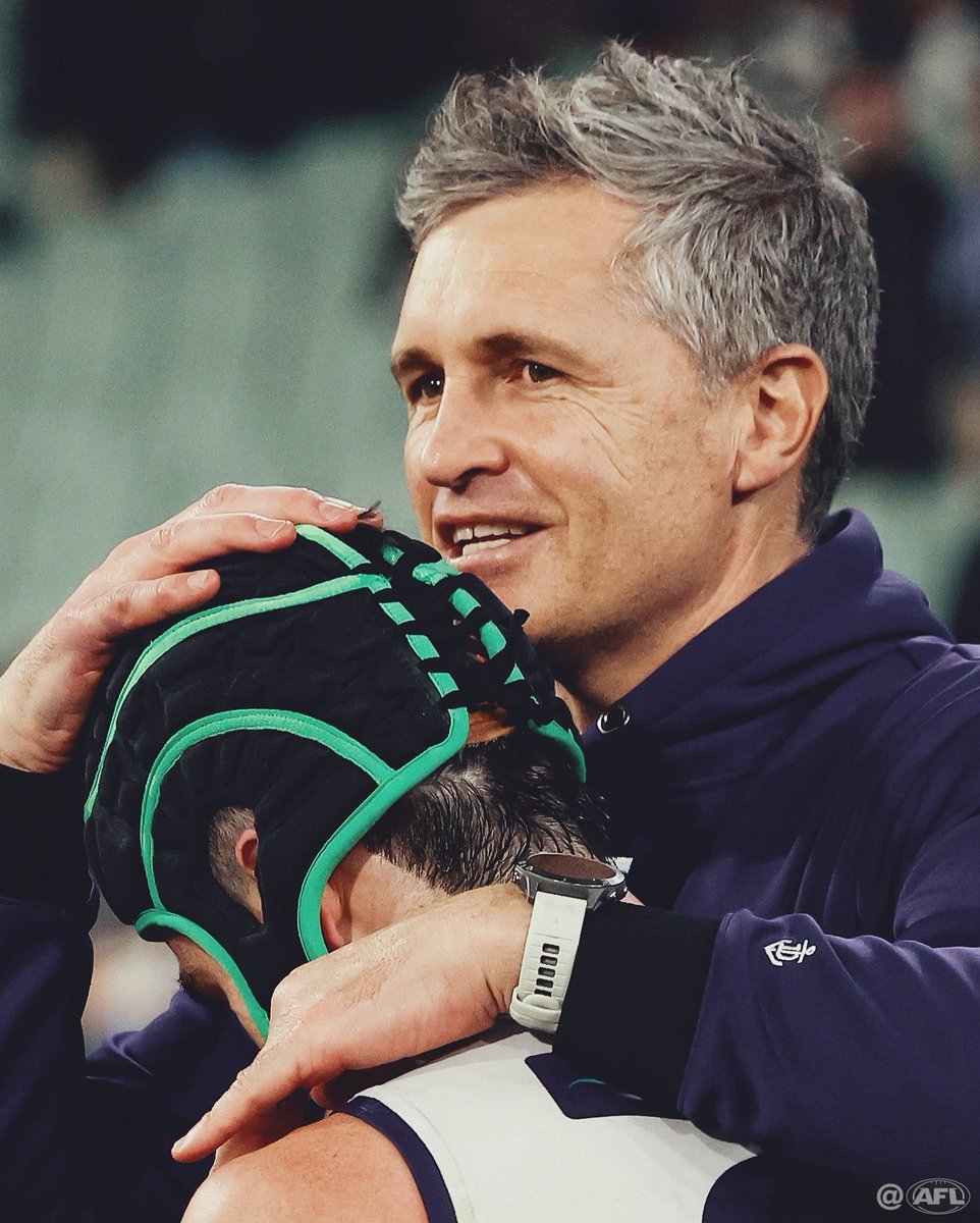 MichaelCWillson's tweet image. Justin Longmuir celebrates with Andrew Brayshaw, wearing brother Angus’ helmet, after a famous Freo victory #AFLPiesFreo