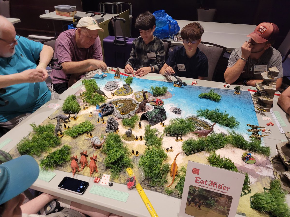 HMGS_Inc's tweet image. Eat Hitler! sent players stomping through the Age of Dinosaurs as hungry carnivores on the hunt for time-traveling Nazis. With each bite, they clawed their way toward the title of King Dinosaur in this fast-paced, toothy finale hosted by Brendan Watts. #Historicon2025