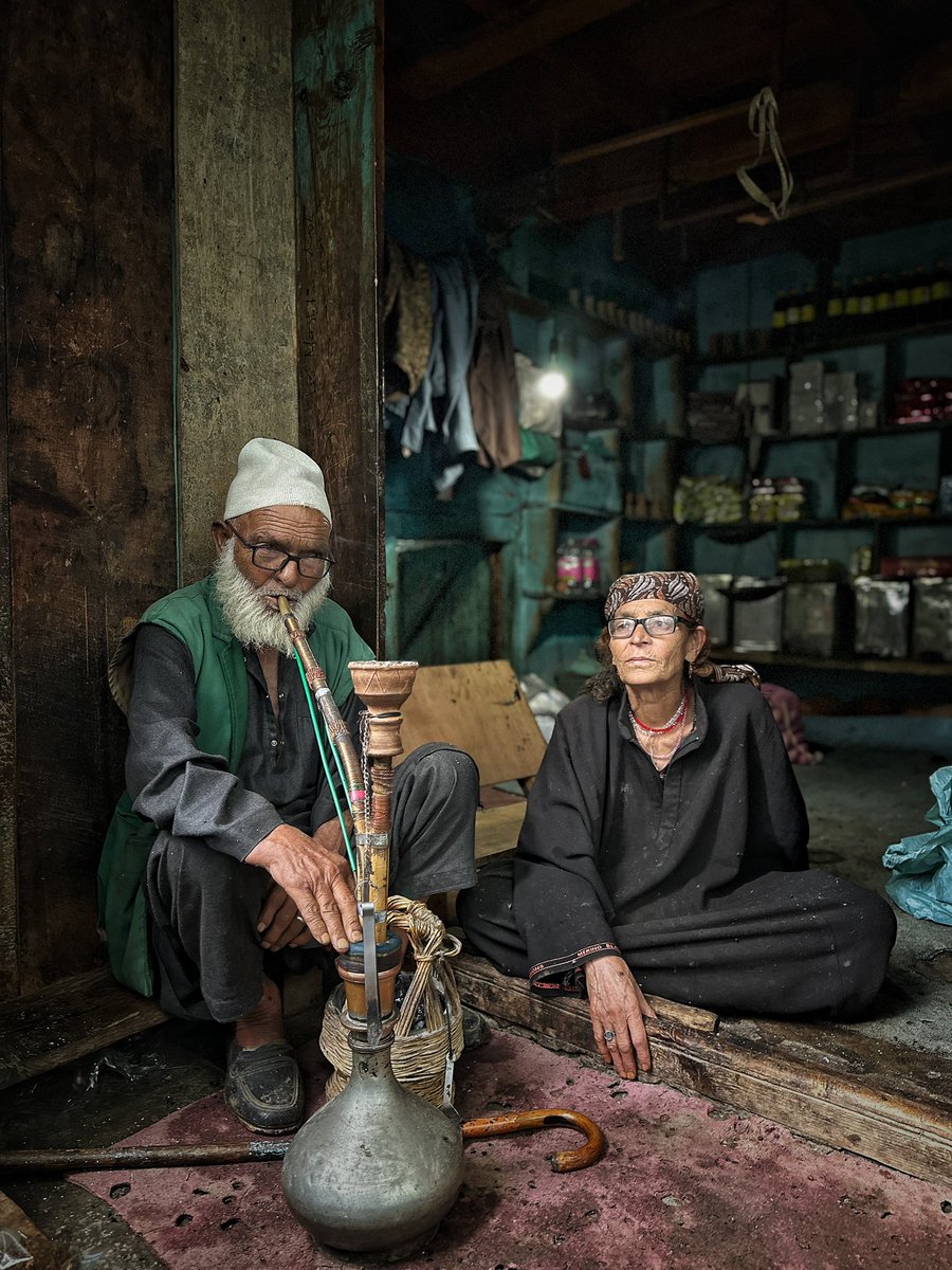 ashishsphotos's tweet image. Somewhere in Hapatnar — a quiet village hidden among the misty pine slopes of Pahalgam — time slows to the rhythm of raindrops. The air is damp, cool, and filled with the earthy scent of wet soil. He draws slowly from his pipe, smoke curling into the rain-soaked breeze, while she…
