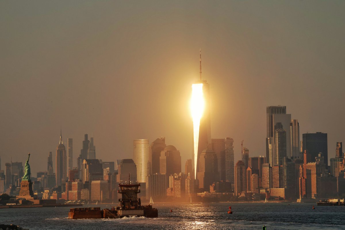 A hot evening in New York City as the setting sun reflects off the windows of One World Trade Center in lower Manhattan, Monday evening #newyork #newyorkcity #nyc #statueofliberty #sunset