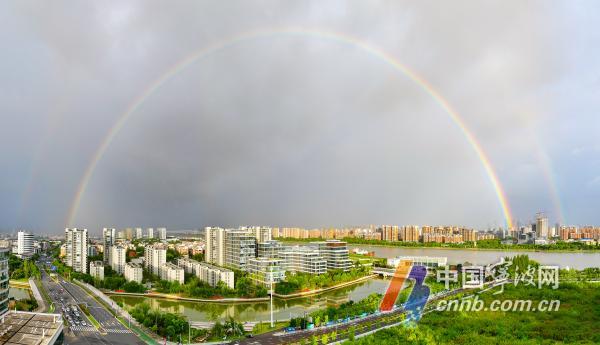 随着今年第8号台风“竹节草”逐渐紧逼，甬城上空时晴时雨。28日傍晚，宁波城区上空出现一道巨大的彩虹。这道“七彩桥”从林立的高楼间拔地而起，横跨天际，为阴云密布的城市增添了一抹亮色。