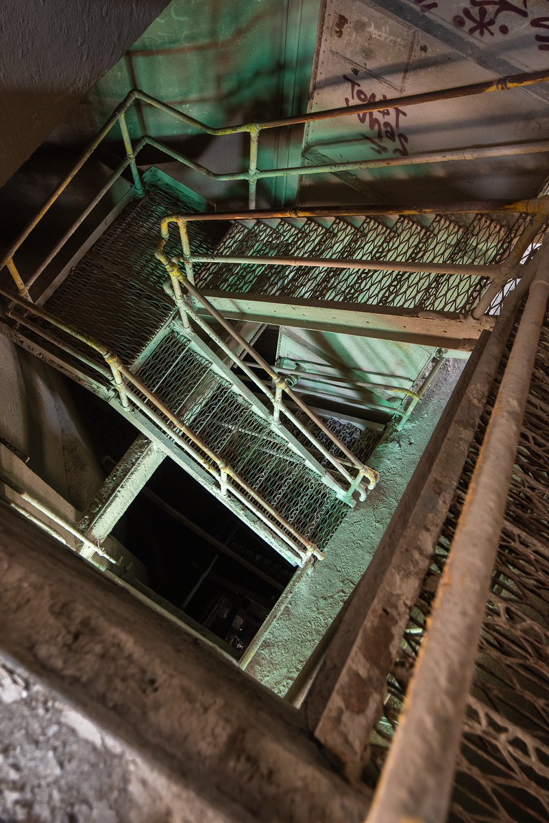ExploresMr's tweet image. A green=tinged and gritty stairwell inside a crumbling silo at an abandoned Ohio concrete plant.