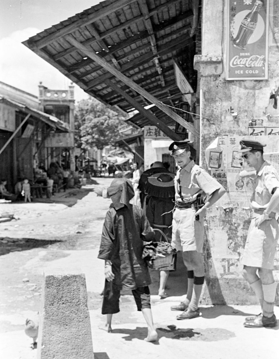 MOFBACN's tweet image. The Coca-Cola border: 1949 photo by Harrison Forman of British colonial officers at the Sha Tau Kok border marker between Hong Kong & Mainland China. There are no visible signs marking each side - only a capitalist Coca-Cola ad on the Hong Kong side subtly signaling the divide.