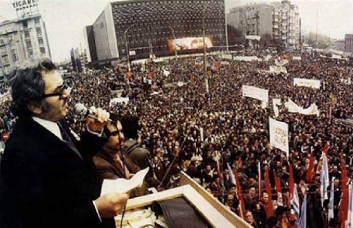 Karanlık bir sabah, evinin önünde sermayenin tetikçileri tarafından katledildi.

Çünkü o bir sınıfı uyandırmıştı.
Çünkü o “örgütlü işçi, yenilmezdir” diyordu.

Bugün hâlâ işçiler güvencesizse, Sendikalar saraya , siyasi partilerin genel merkezlerine bağlıysa,

Her direniş, Kemal