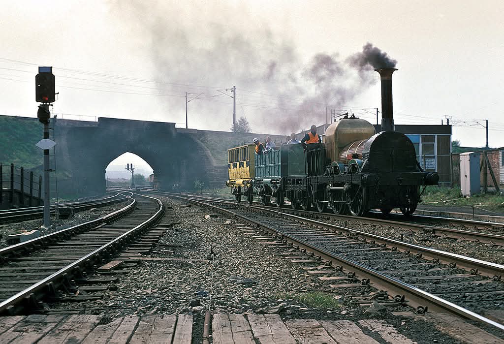 adipullenLNER's tweet image. L&amp;amp;MR Lion with replica stock, makes her way from Southport to Bold Colliery on 18/5/1980 transfer move in readiness for the Rocket 150 celebrations at Rainhill that year. Seen entering Wigan Wallgate. An incredible sight, with the 25kv electrified WCML in the background
📸Unknown