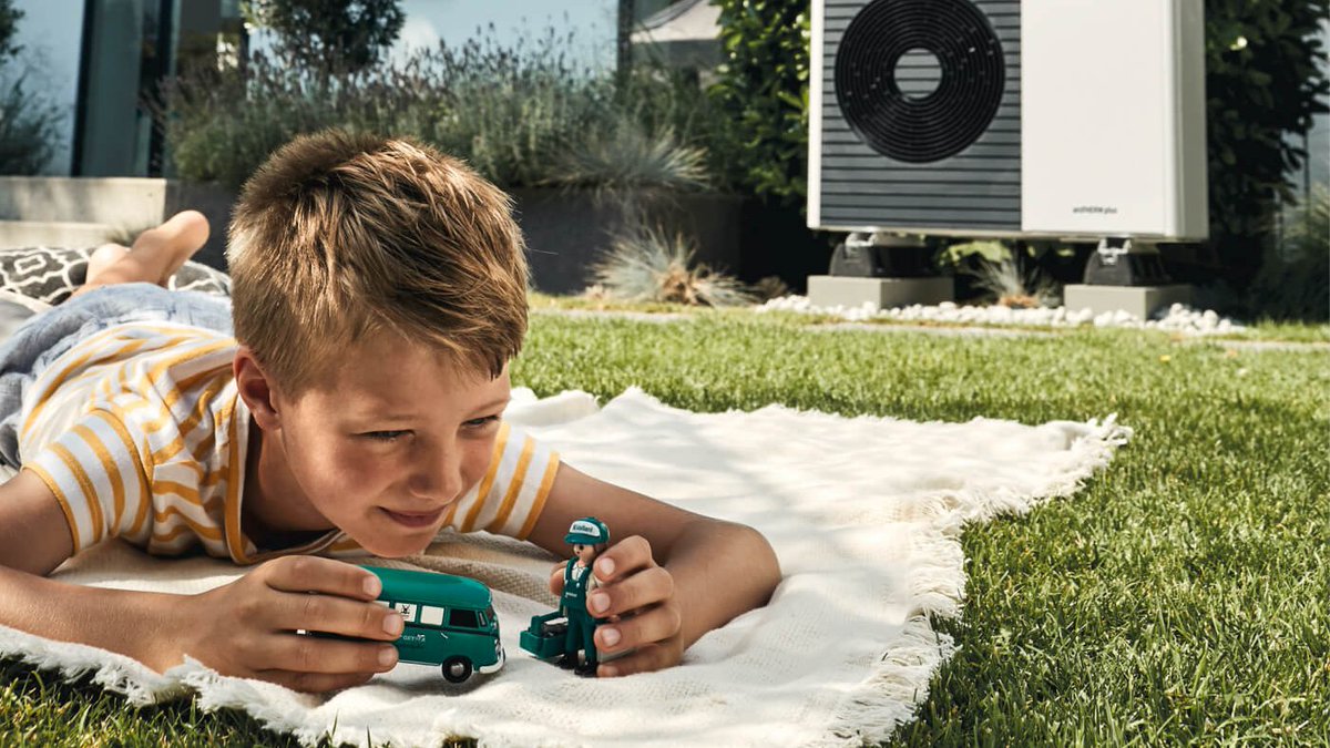 Boy plays with toys in front of an Air Source Heat Pump