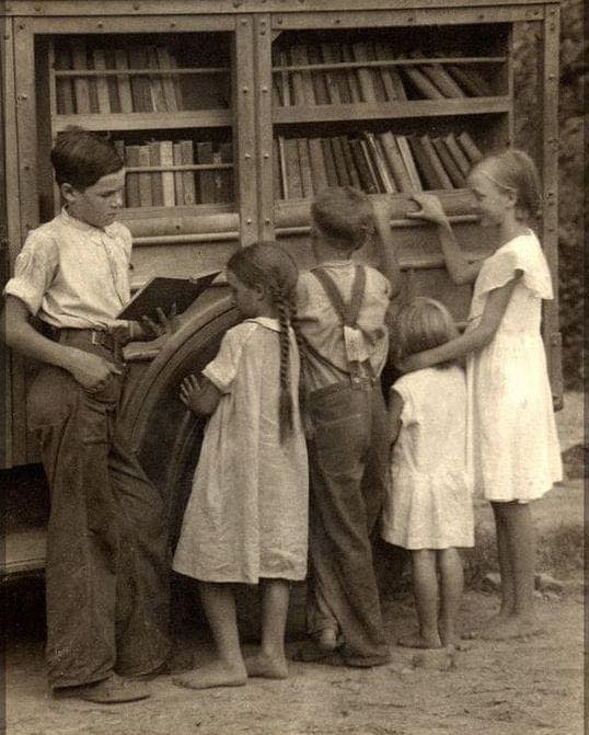 HistoryUnd's tweet image. Barefoot kids at a mobile book cart in the Appalachian Mountains.