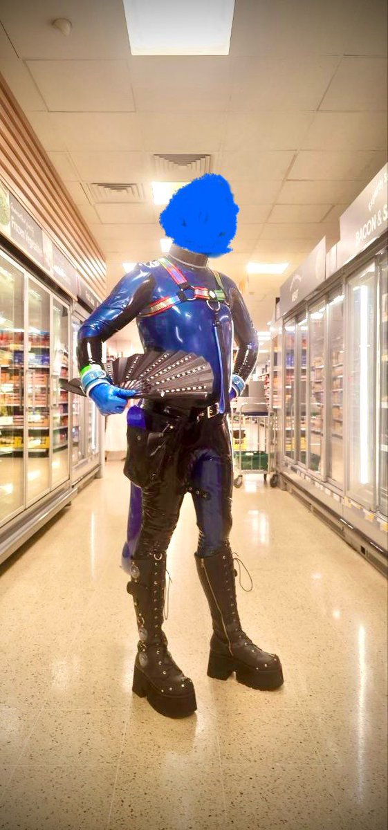 Polytherian's tweet image. On the way to a rubber club night dressed up as a shiny rubber dog (tail behind me!) and taking a nice break in the chiller aisle at a passing shop to cool down!