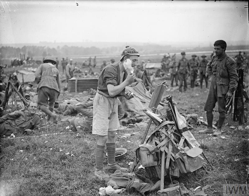 WW1IEPER1917's tweet image. Anzac back at rest after the taking of Pozieres, by the 1st ANZAC Division, 23rd July 1916. Australian soldier having a shave while wearing a captured German pickelhaube. IWM Q 4041