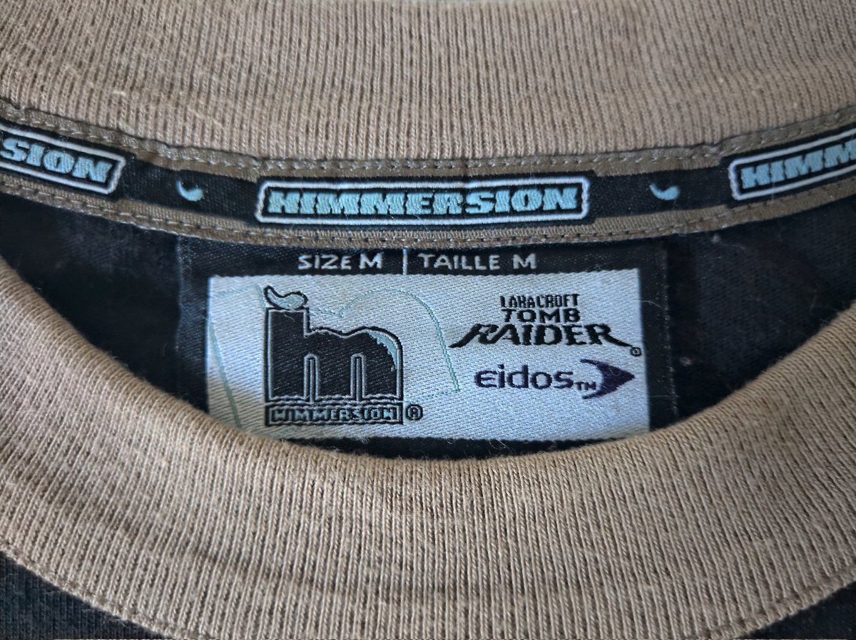CiskoNokia's tweet photo. Nueva #rertro adquisición para añadir a mi inmensa Croftlección 😎
Camiseta de invierno oficial basada en el juego Tomb Raider El ángel de la oscuridad de color negra con varios bordados y primera vez que alguien me regala semillas para plantar flores 👀😁 https://t.co/AhZBOrvW0z
