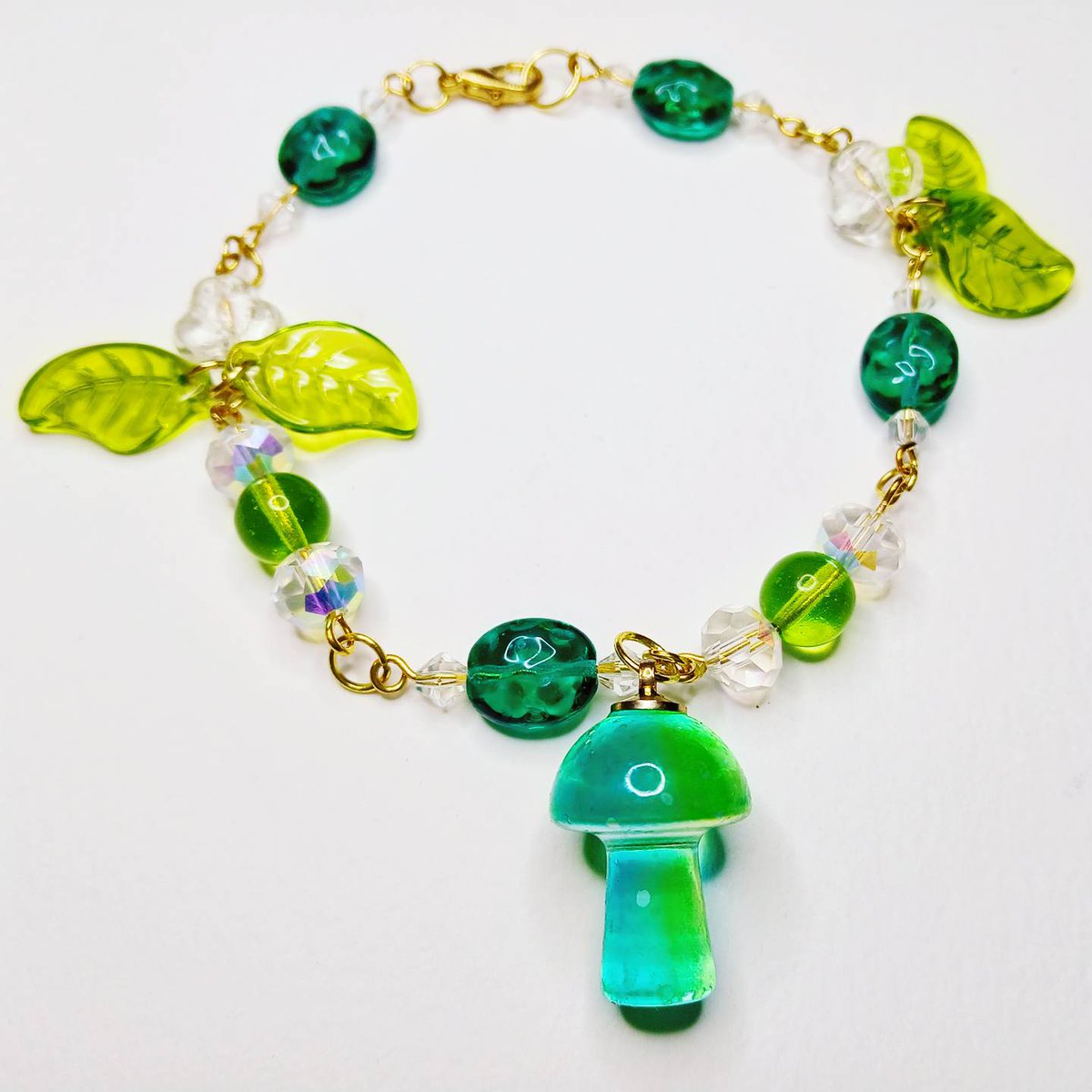 SEEyourVIBE's tweet image. Step into a storybook with the Forest Whimsy Bracelet - a handcrafted piece inspired by the magic of nature. Featuring green and white beads accented with gold details, delicate leaf charms, and a charming glass mushroom pendant, this bracelet brings woodland vibes to life.