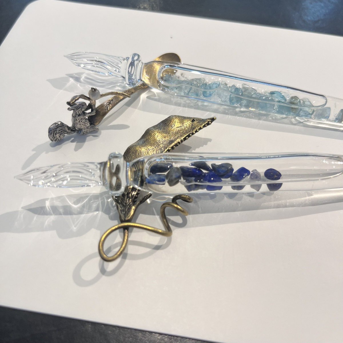 DT_stylo's tweet image. まつぼっくりのガラスペンのご紹介
上がアパタイト、下がラピスラズリのストーン、一緒に入っているストームグラスは気温によって表情を変えます。
ペンレストは佐々木ひとみさんの作品。
また7/26(土)にはまつぼっくりオリジナルガラスペン受注会を開催。お好きなストーンでガラスペンが作れます。