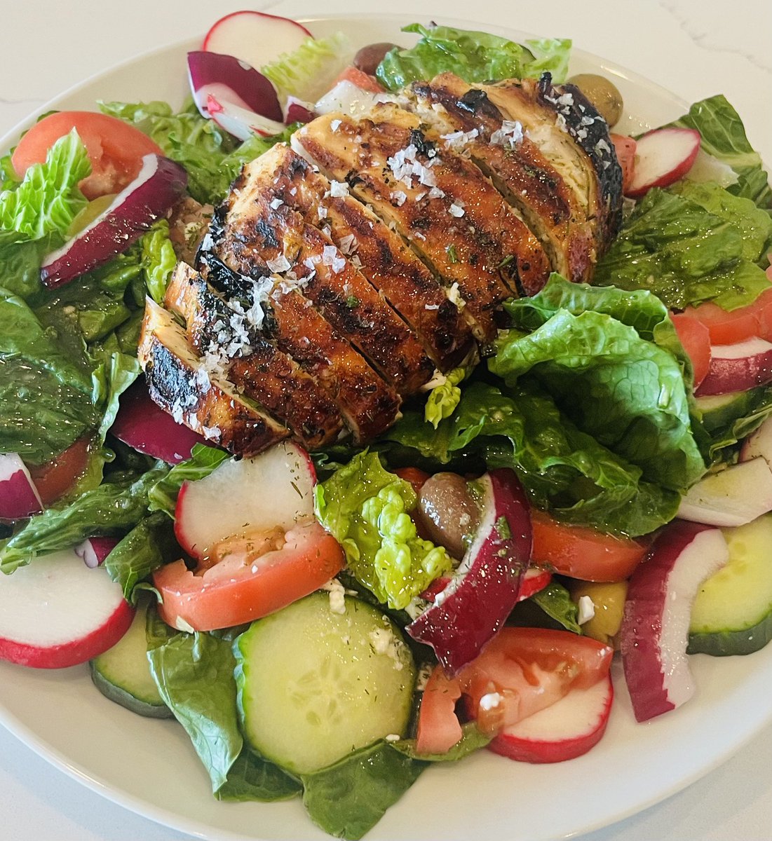 Behold, a delicious grilled chicken breast atop a fresh salad with tomatoes, cucumbers, radishes, and olives! Perfect for a healthy meal. Who’s in? 🍗🥗 #HealthyEating #Foodie