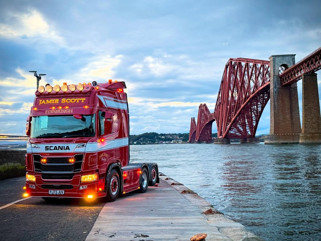 ScaniaUK's tweet image. Standing with its back to the mighty Forth Bridges, Jamie Scott’s glorious #scania truck prepares to leave the water behind and take on the miles ahead.
Isn’t it a spectacular sight, with its lights glowing in the evening sun?