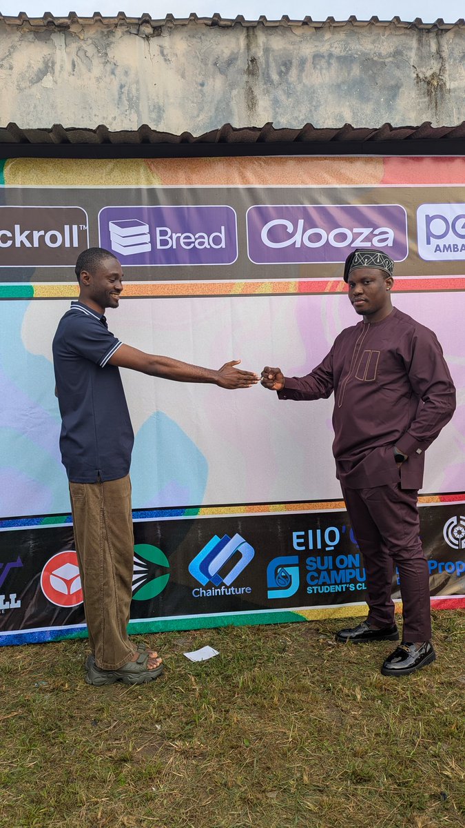 Two individuals shaking hands in front of a banner with various blockchain company logos