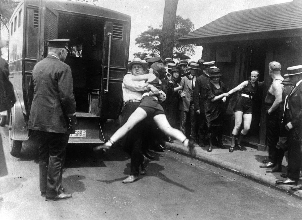 Women being arrested for wearing one piece bathing suit without the required leg coverings, Chicago. Photographed in 1922.