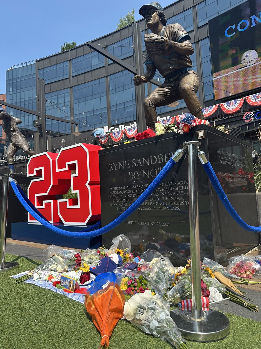 Fans stopping by the Ryno statue and leaving flowers, hats, baseballs.