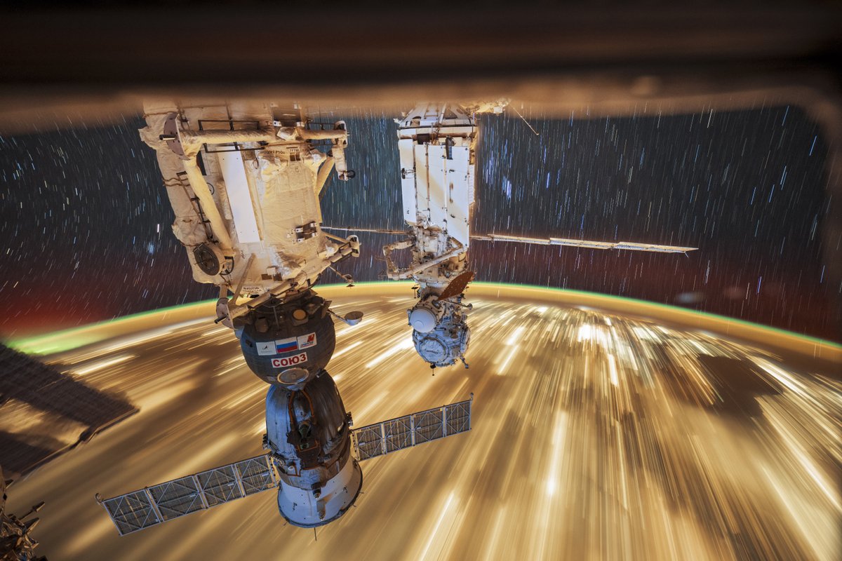 City lights at night, streaked by orbital speeds with time exposure, create a golden path seen only from space.