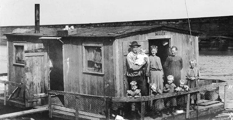 A fisherman and his family aboard their tiny shanty boat on the Mississippi River, Missouri, 1914.