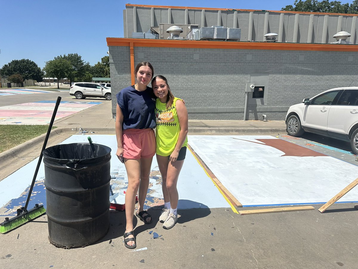 Evelyn gelo And Evelyn Marquez, seniors at Nocona outside on  hot day Painting their senior parking spot!