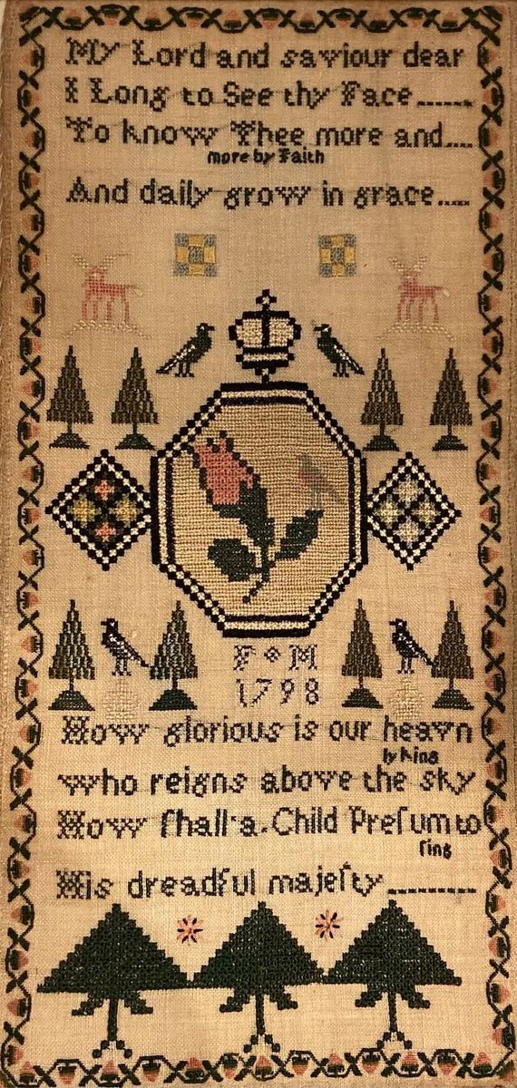 This sampler, with a central medallion which looks quite modern, was stitched by a girl with the initials "FM" in 1798. In the centre is a pink rose in an octagonal frame, flanked by diamonds, trees, birds, and a crown. The sampler's use of pink and black makes it extra striking