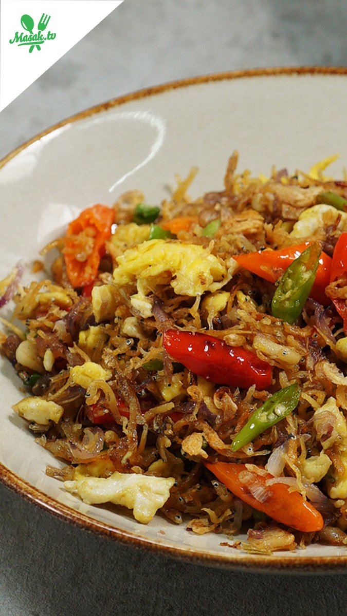 Close-up of an Indonesian dish (Nasi Goreng) with fried rice, small dried fish (ikan teri), scrambled eggs, and red and green chilies, branded with 'Masak.tv' logo.